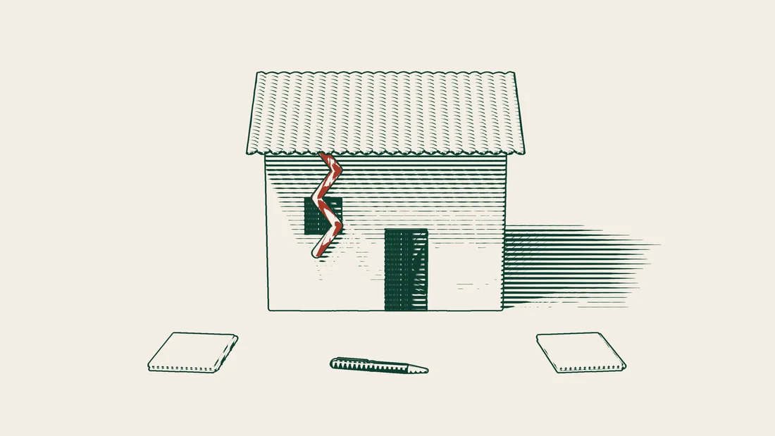 A house with a tiled roof and a red crack in its wall, with two separate stacks of blank contracts and a fountain pen in front.