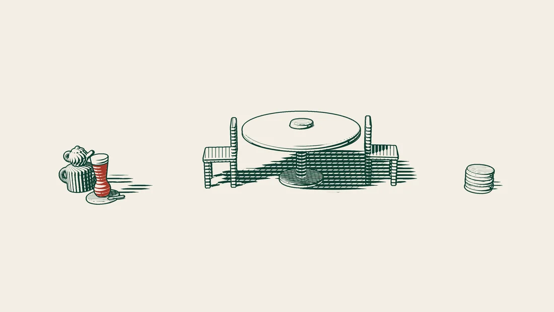 A table with two empty chairs facing each other, a small stack of coins on it beside a much larger stack.