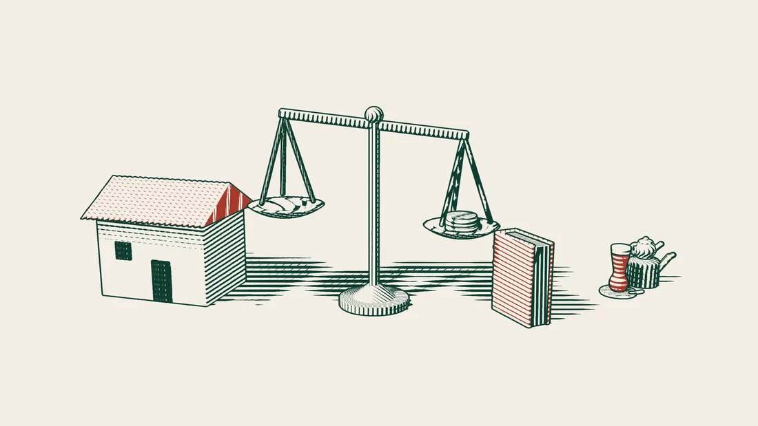 A pair of scales with a stack of coins on one pan, beside a red-bound book and a house.