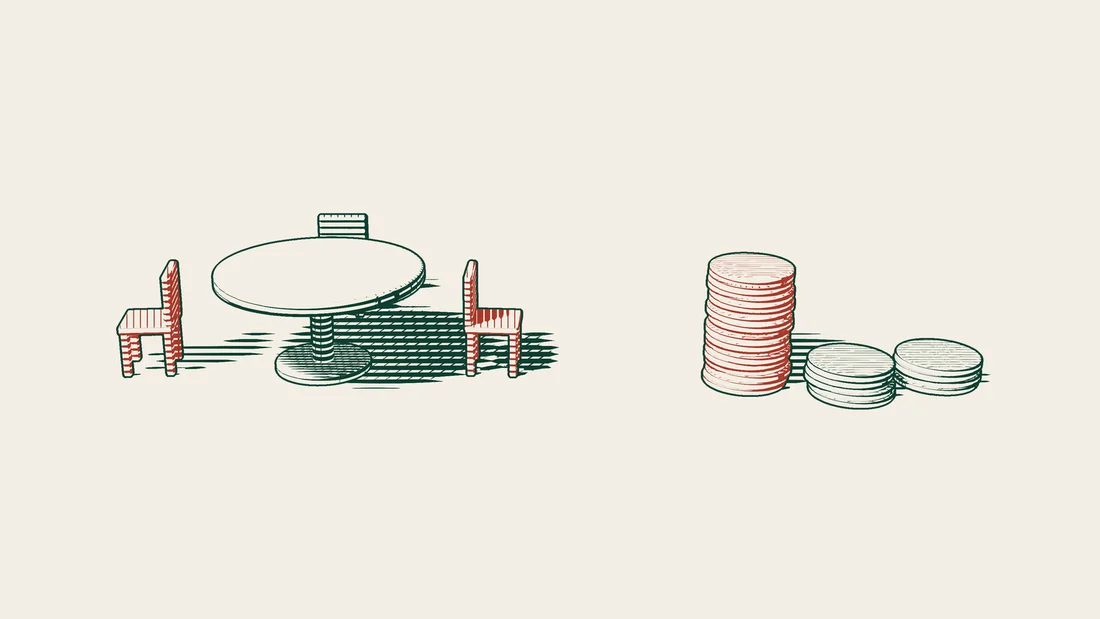 A round table with three chairs, two of them red, and beside it three coin towers, the tallest of which is red.