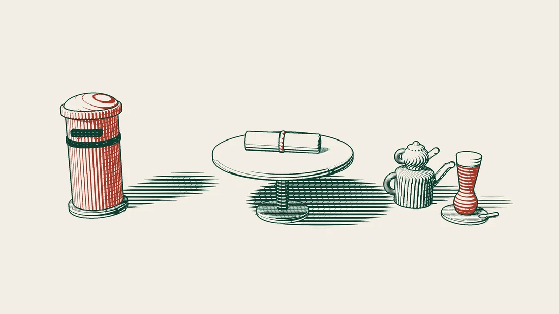 An old ribbon-tied scroll on a round table, with a red postbox on one side and a Turkish tea set on the other.