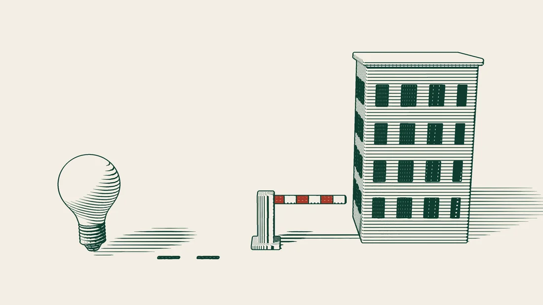 A closed barrier cuts off the road to an apartment building, with a light bulb beside it.
