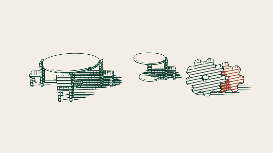 A large table ringed with many chairs, a small table with two chairs beside it, and two interlocking cogwheels.