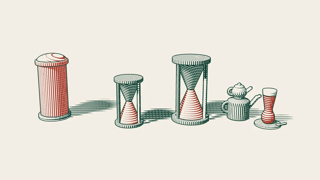 Two hourglasses of different heights stand between a red postbox for the UK and a Turkish tea set with a tulip glass and double teapot.