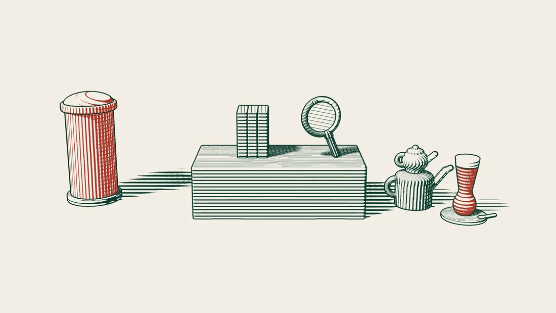 File folders and a magnifying glass on a desk, with a red UK postbox on one side and a Turkish tea set on the other.